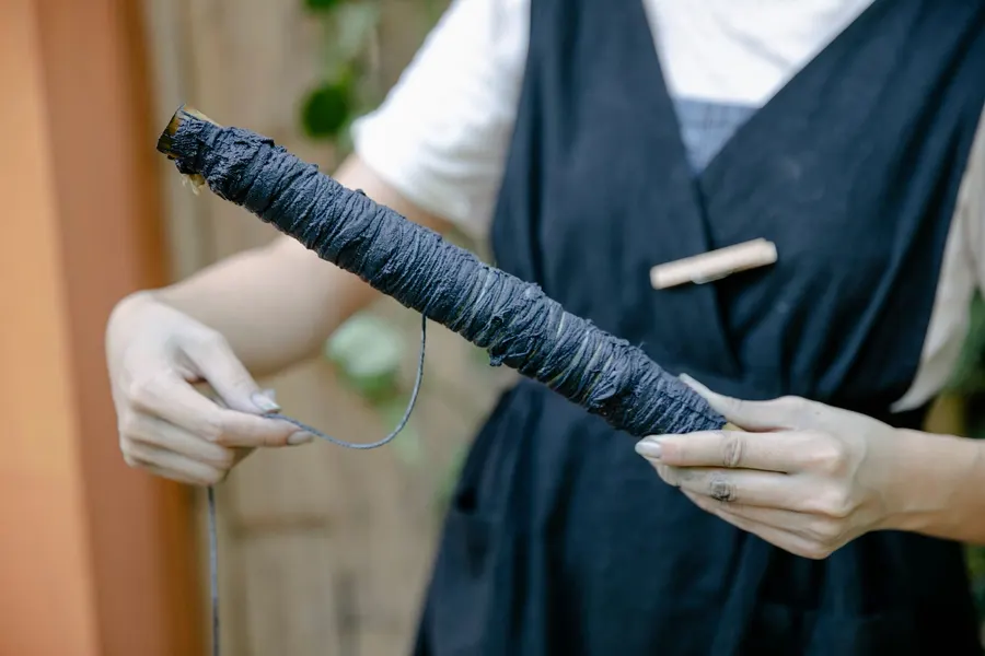 藍染めの布の束に糸を巻きつける手元